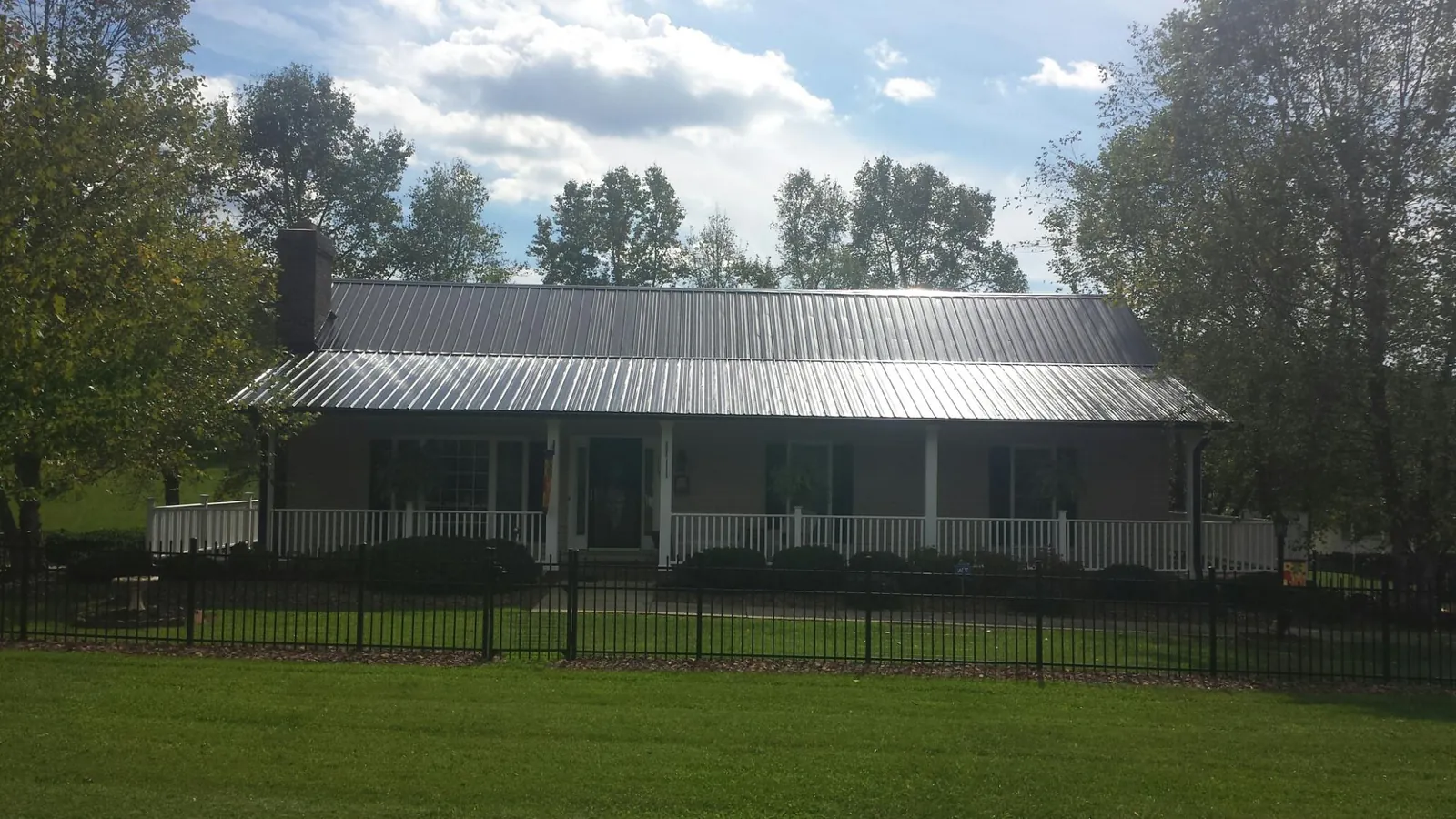 Gray metal roof on a brick ranch with a full width front porch — Gutter Guard Installation work by our crew in Warren
